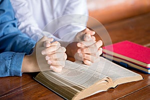 Hands folded in prayer on a Holy Bible