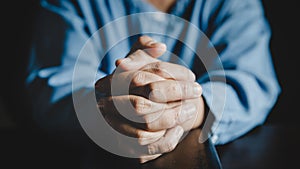 Hands folded in prayer on a Holy Bible