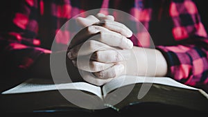 Hands folded in prayer on a Holy Bible