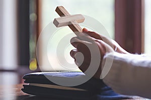 Hands folded in prayer on a Holy Bible in church concept for fa