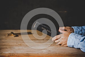 Hands folded in prayer on a Holy Bible in church concept for faith