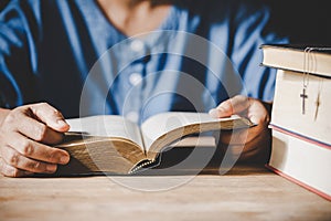 Hands folded in prayer on a Holy Bible in church concept for faith