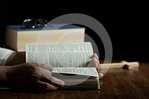 Hands folded in prayer on a Holy Bible in church concept for faith