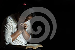 Hands folded in prayer on a Holy Bible in church concept for faith