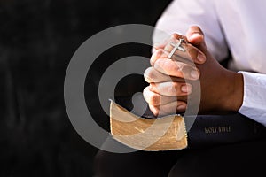 Hands folded in prayer on a Holy Bible in church concept for faith