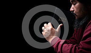 Hands folded in prayer on a Holy Bible in church concept for faith, spirituality and religion, man praying in morning. Man hand