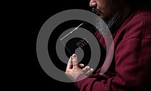 Hands folded in prayer on a Holy Bible in church concept for faith, spirituality and religion, man praying in morning. Man hand