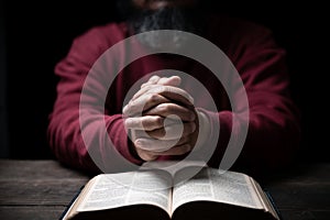 Hands folded in prayer on a Holy Bible in church concept for faith, spirituality and religion, man praying in morning. Man hand