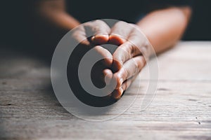 Hands folded in prayer on a Holy Bible in church concept for faith, spirituality and religion, woman praying on holy bible in the