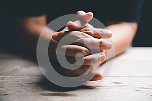 Hands folded in prayer on a Holy Bible in church concept for faith, spirituality and religion, woman praying on holy bible in the