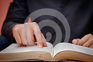 Hands folded in prayer on a Holy Bible in church concept for faith, spirtuality and religion