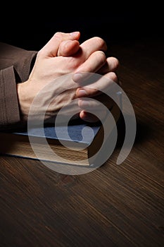 Hands folded in prayer over a Holy Bible