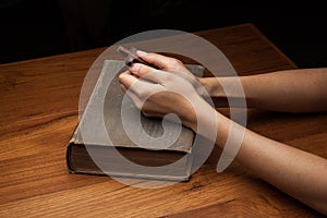 Hands folded in prayer over Holy Bible