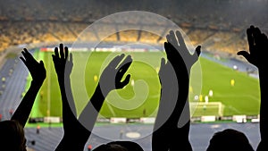 Hands of football fans, cheering team during match on overcrowded stadium