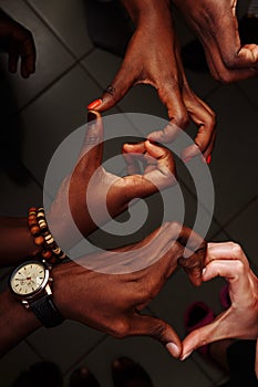 Hands in the form of heart of happy group of multinational African, latin american and european people which stay