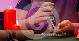 Hands of a fortune teller shuffling tarot cards by candlelight, preparing for a mystic reading session