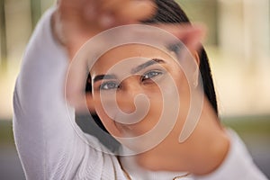 Hands, frame and eyes with a woman looking through her fingers while framing her face outdoor. Portrait, girl and happy