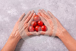 Hands with freshly harvested tomatoes on the table. Womans hands and cherry tomatoes
