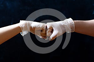 Hands of friends in medical gloves greeting each other with fist bump.