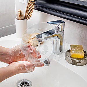 Hands frothing with soap with tap water for disinfection and beauty