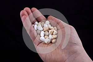 Hands full of pils on black background