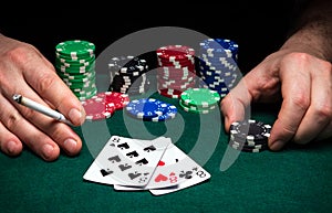 Hands of a gambler closeup and chips on green table in a poker club. A player places a bet on winning poker  three of a kind or