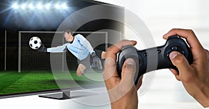 Hands with game controller in front of tv screen with goalkeeper reaching out the ball