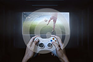 Hands with game controller playing football video game