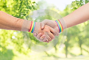 Hands with gay pride wristbands make handshake
