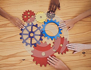 Hands, gears and collaboration with a team of people working with cogs and equipment on a table in the office. Teamwork
