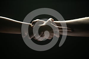 Hands gesturing on black background. Giving a helping hand. Support and help, salvation. Strength strong hads of two