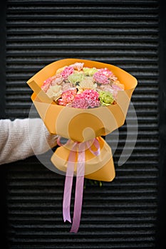 Hands of the girl with a bouquet of carnations on a dark background