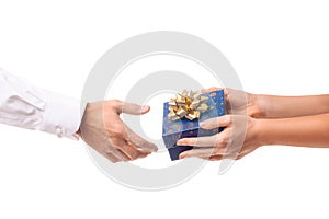 Hands of a girl give a gift in a blue box with a gold bow to a man in a white shirt, white isolated background. Concept of new