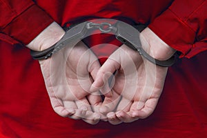 Hands of the girl in handcuffs. red clothes.