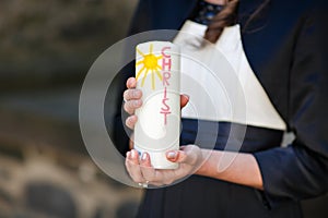 Hands of girl holding candle with crucifix for holy confirmation or communion.