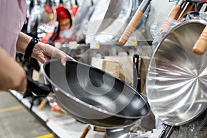 Hands of girl holding a new pan,choosing black teflon frying pan,asian  customer deciding to buy non-stick frying pan for cooking