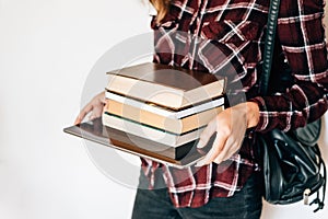 Hands of a girl holding a tablet and a stack of books. The concept of knowledge. copy space