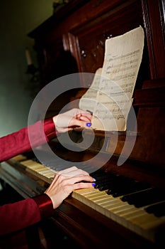 Hands of the girl on the keys of a musical instrument piano