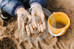 Hands of a girl plaing with sand on a shore