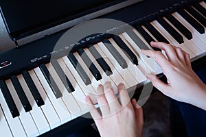 Hands of girl playing piano, selective focus. Musical instrument grand piano with woman performer.