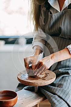 Hands of a girl on a Potter`s wheel with clay. The process of creating pottery.