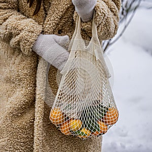 Hands of girl with reusable cotton shopping mesh bag with citrus fruits. Concept of No plastic, Zero waste, plastic free