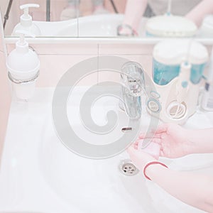 Hands of girl with soap in sink under faucet with water in the bathroom. Concept of hygiene, disinfection, protection