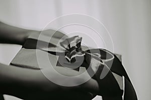 Hands of a girl, women hold a paper gift box with a red bow on a white background. Celebrate