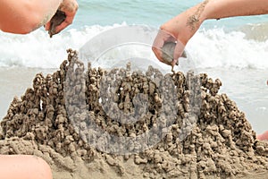 Hands of girls playing with sand on the beach