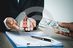 Hands giving house model to other hands with money. Concept of real estate