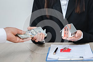 Hands giving house model to other hands with money. Concept of real estate and deal