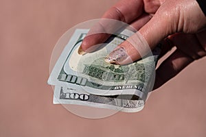 Hands giving money like a bribe or tips. Holding US dollars banknotes on a blurred background, US currency