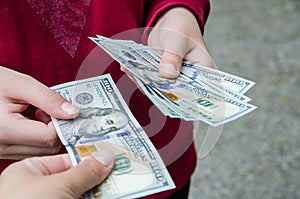 Female hands giving or paying money to a person, dollar bills - credit, bribery and financial concepts