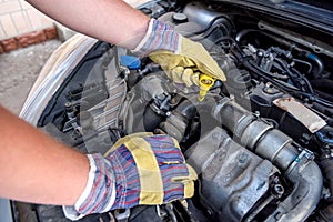 Hands in gloves with car engine close up